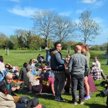 A group sitting on blankets on the grass in spring sun