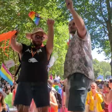 Two people dancing with flags at a Pride parade